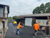two men working on a driveway with a broom