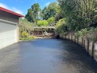 a driveway with a garage and bushes in the background