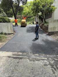 a man is laying asphalt on a driveway