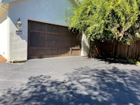 a driveway with a garage and a tree