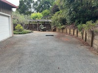 a driveway with bushes and trees in the background