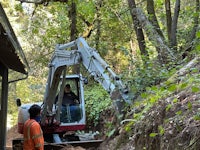 an excavator is being used to dig a hole in the woods