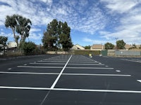 a parking lot with white lines and trees in the background