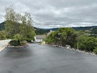 a black paved driveway with trees in the background