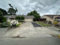 a house with a driveway and bushes in front of it