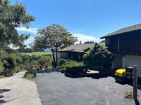 a driveway leading to a house with trees in the background