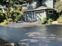 a driveway with a garage and trees in the background