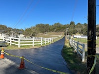 a road with a white fence and yellow tape