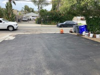 a black paved driveway with a car parked next to it