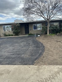 a driveway in front of a house with a tree in the middle